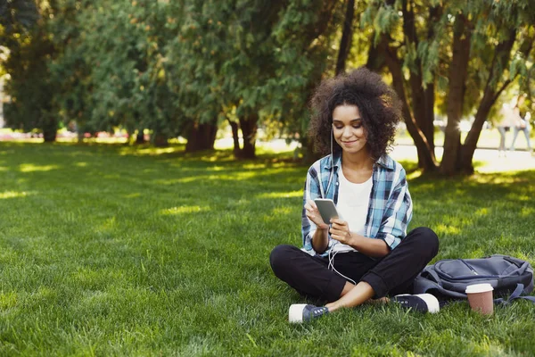 Mujer joven escuchando música en la hierba al aire libre — Foto de Stock
