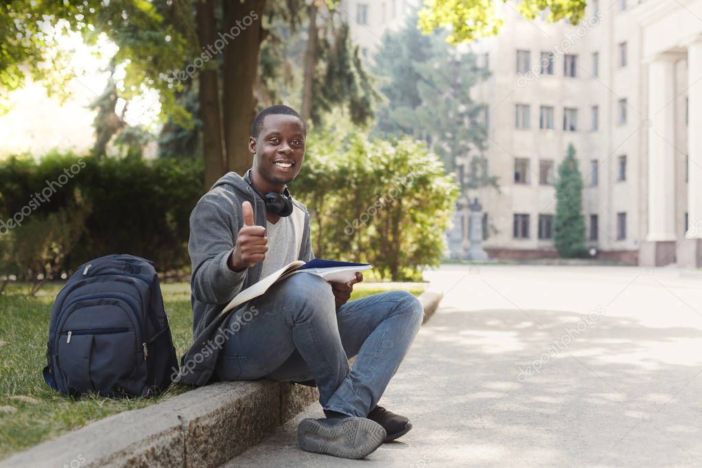 African-american student sitting with notebook in university campus