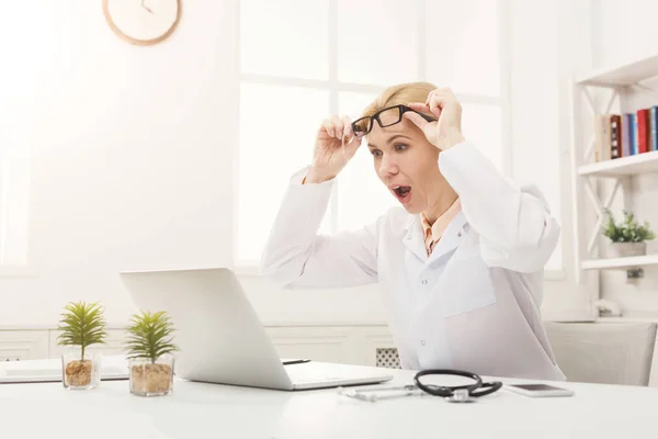 Medico scioccato con gli occhiali seduti sul desktop — Foto Stock