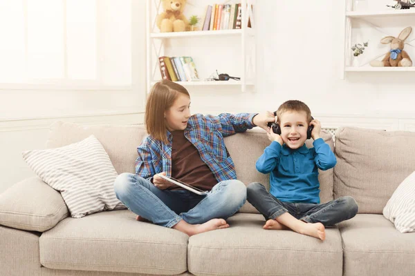 Two kids listening music on couch at home — Stock Photo, Image