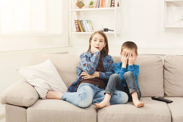 Frightened children watching TV at home