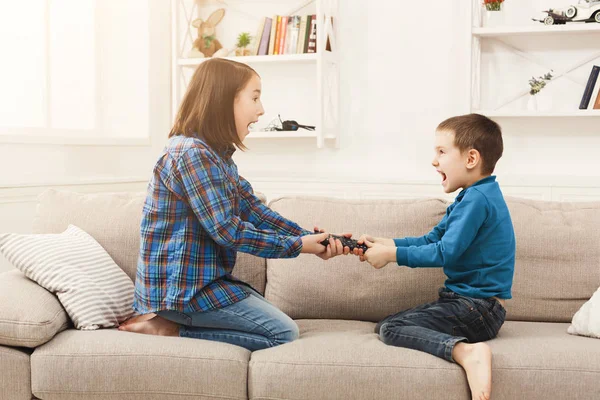 Siblings fighting over remote control at home — Stock Photo, Image