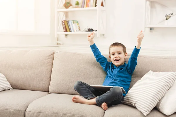 Niño pequeño usando tableta digital en el sofá en casa —  Fotos de Stock