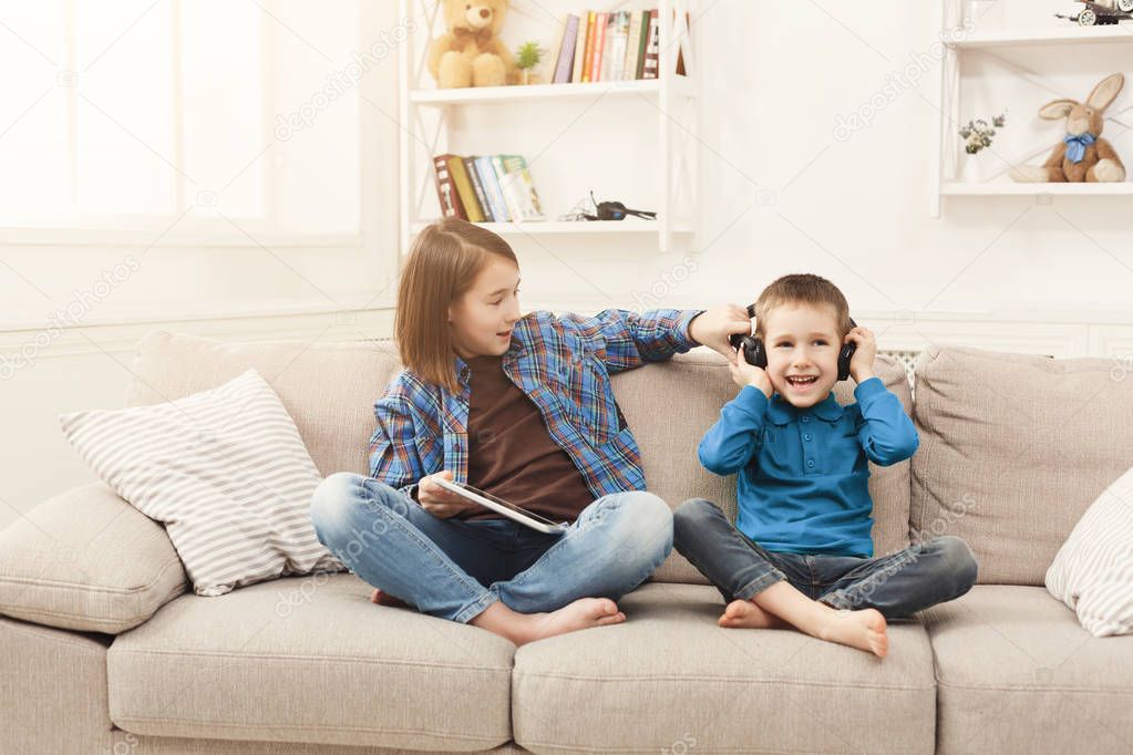 Two kids listening music on couch at home