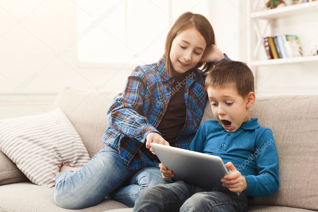 Young girl reading tablet for her brother