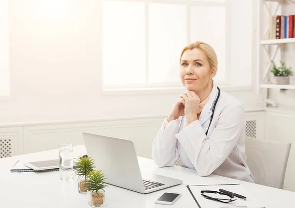 Portrait de femme médecin assise sur le bureau — Photo