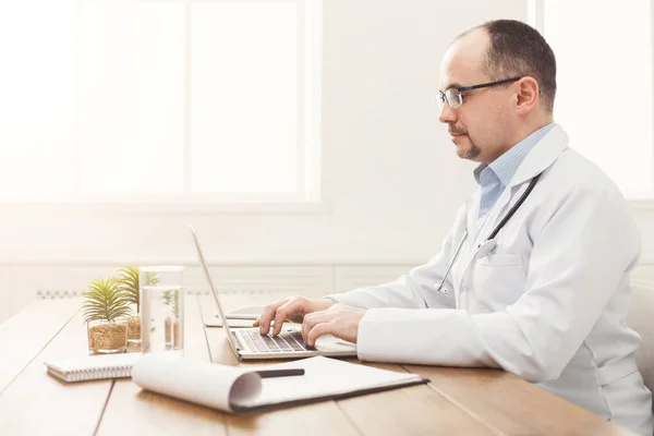 Serious doctor in glasses sitting at the desktop — Stock Photo, Image