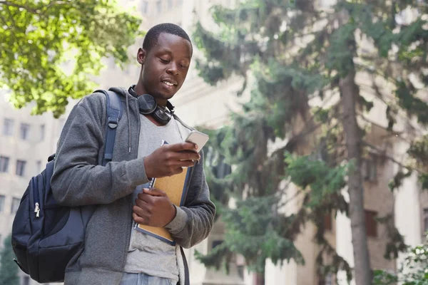 Feliz estudante afro-americano que envia mensagens no campus universitário — Fotografia de Stock