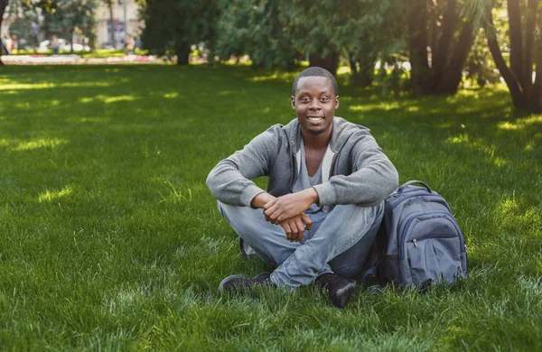 Glad afro-amerikansk student sitter i universitetsområdet utomhus — Stockfoto