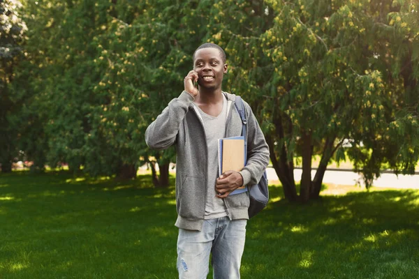 Fröhliche afrikanisch-amerikanische Studentin spricht im Park auf dem Smartphone — Stockfoto