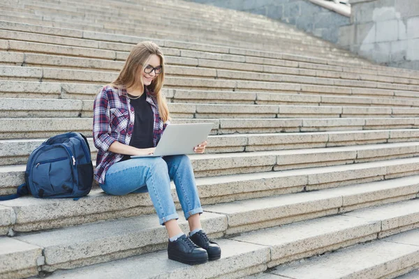 Usmívající se student sedí na schodech pomocí přenosného počítače — Stock fotografie