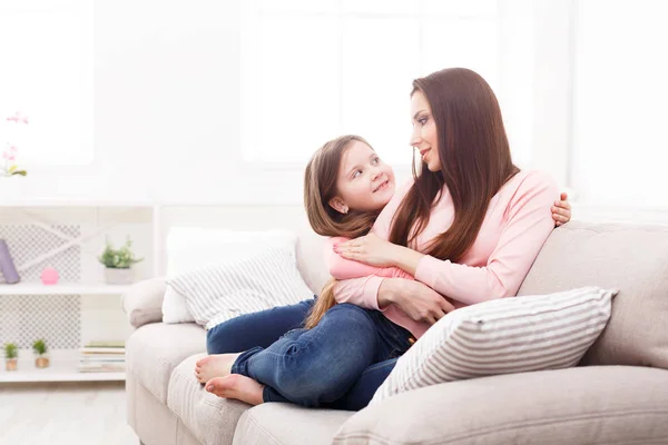 Mutter mit ihrer süßen kleinen Tochter sitzt auf dem Sofa. — Stockfoto