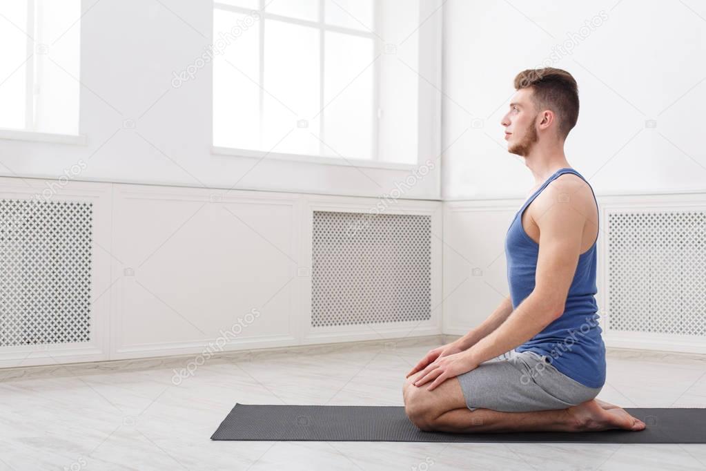 Man training yoga in hero pose, side view
