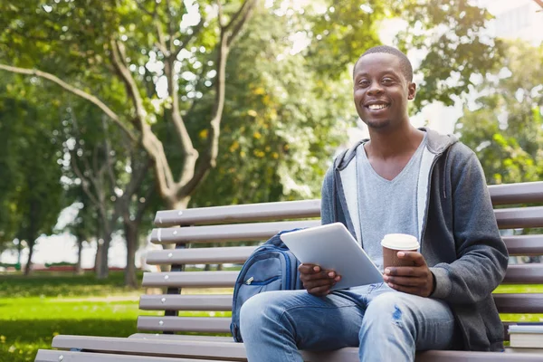 Estudante afro-americano sorridente no parque com tablet oudoors — Fotografia de Stock