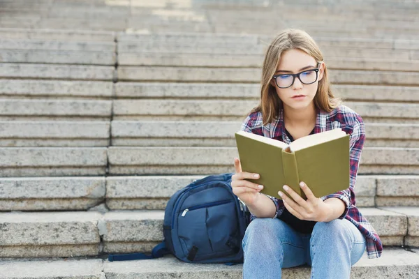 Jonge vrouw lezen boek op trappen van Universiteit — Stockfoto