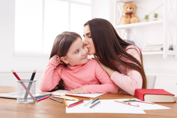 Moeder zit met haar dochter thuis haar wang kussen — Stockfoto