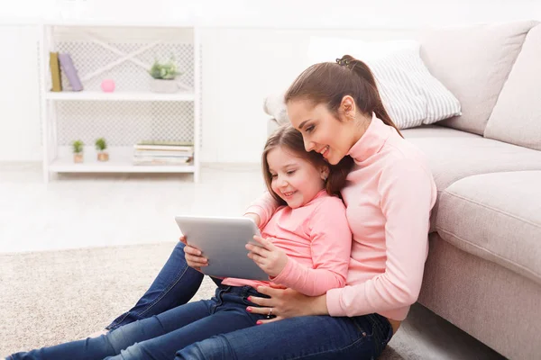 Niña y su mamá usando una tableta en casa —  Fotos de Stock