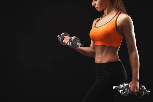 Unrecognizable athletic woman with dumbbells