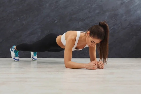 Fitness donna plank allenamento su sfondo grigio all'interno — Foto Stock