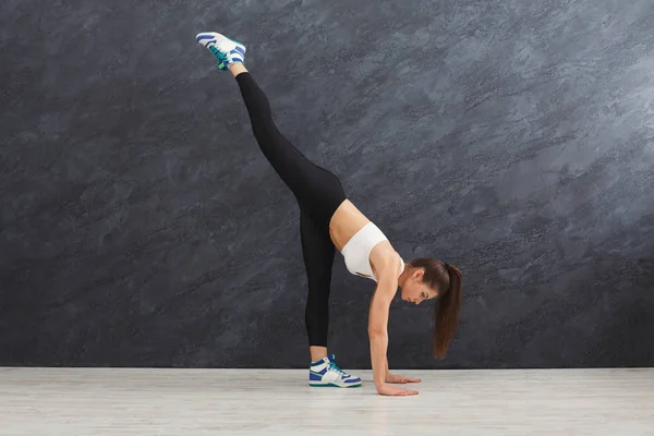 Fitnessfrau dehnt sich vor grauem Hintergrund drinnen — Stockfoto