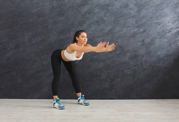 Fitness vrouw uitrekken op grijze achtergrond binnenshuis — Stockfoto