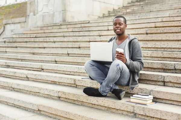 노트북을 사용 하 여 커피와 계단에 앉아 웃는 아프리카계 미국인 학생 — 스톡 사진