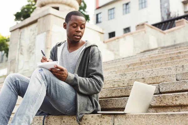 Συμπυκνωμένο Αφρικανικός-Αμερικανός φοιτητής που σπουδάζει με laptop και μικρόs φορήτοs σε εξωτερικούς χώρους — Φωτογραφία Αρχείου