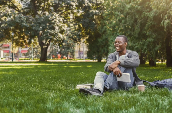 Heureux étudiant afro-américain assis avec ordinateur portable sur l'herbe — Photo