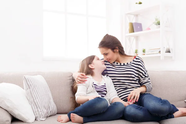 Mother with her cute little daughter sitting on the sofa.