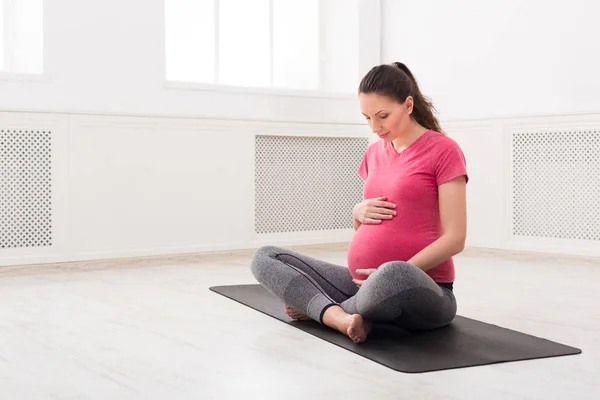 Menina grávida sentado em pose de lótus, acariciar sua barriga — Fotografia de Stock