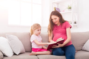 Küçük kız ve annesi evde kitap okuma