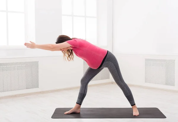 Gravid kvinna warmup stretching tränar inomhus — Stockfoto