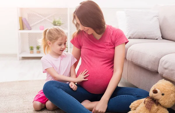 Klein meisje raakt haar zwangere moeder buik — Stockfoto