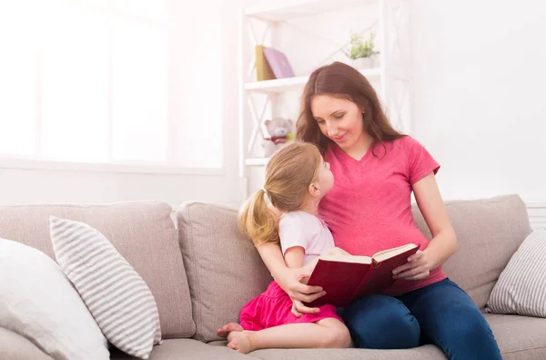 Liten flicka och hennes mamma som läser bok hemma — Stockfoto