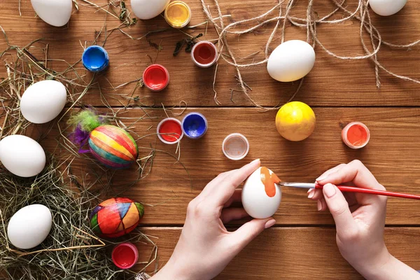 Painting colorful easter eggs, top view on wood