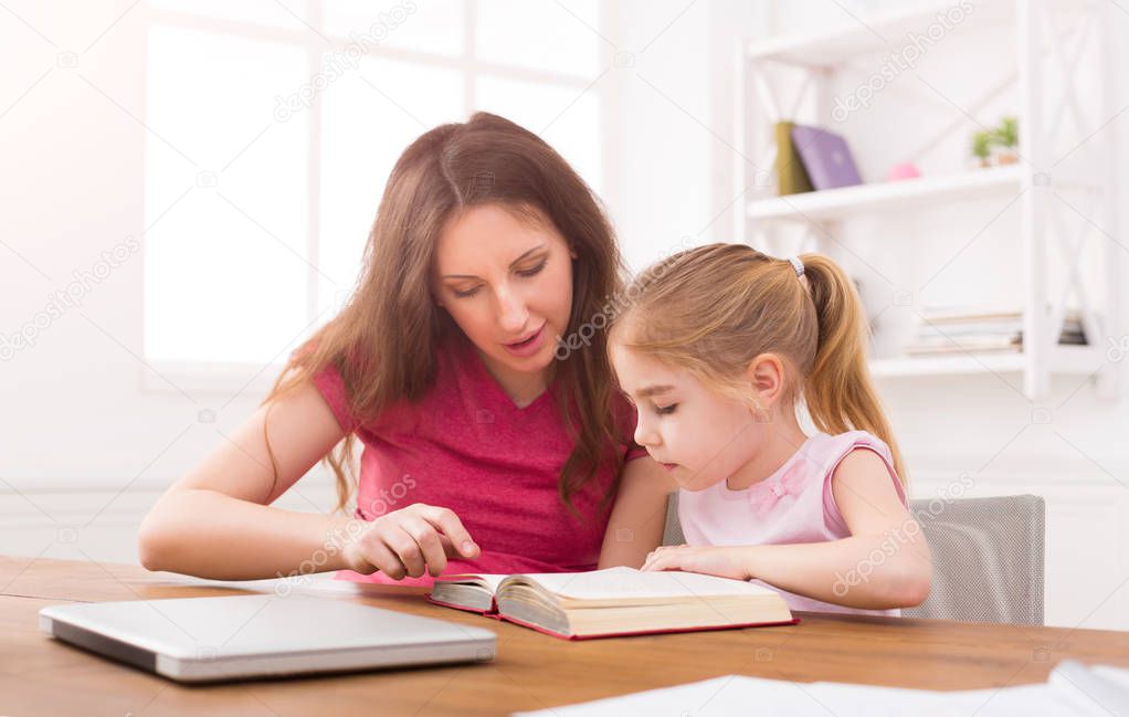 Mother helping her daughter with homework.