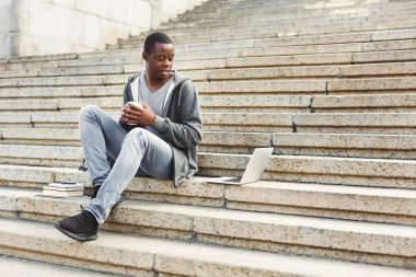 Laptop ve kahve açık havada olan yakışıklı Afrikalı-Amerikalı adam