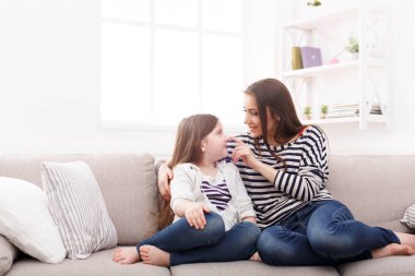 Kanepede oturan sevimli küçük kızı annesiyle.