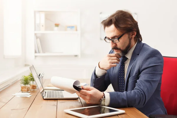 Fundersam affärsman läsning rappor i office — Stockfoto