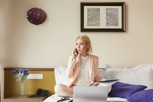 Donna d'affari seduta sul letto e utilizzando il computer portatile — Foto Stock