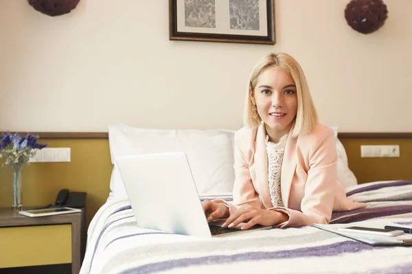 Happy businesswoman lying on bed and using tlaptop