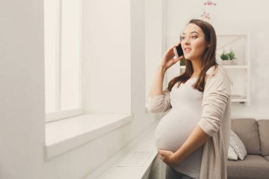 Gülümseyen hamile kadın onun smartphone üzerinde söz