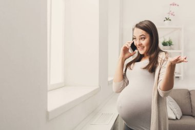 Gülümseyen hamile kadın onun smartphone üzerinde söz