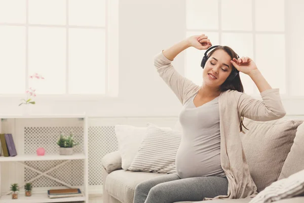 Zwangere vrouw luisteren muziek in hoofdtelefoon — Stockfoto