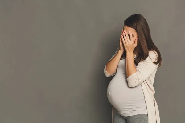 Плаче вагітна жінка, сірий студійний фон — стокове фото