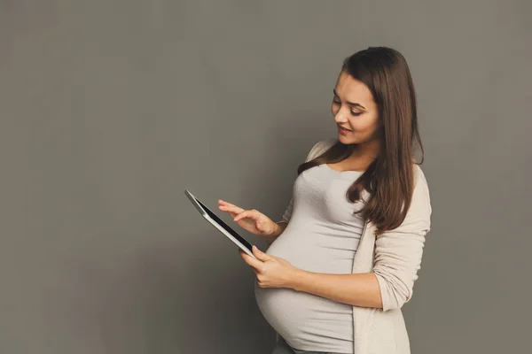 Щаслива вагітна жінка використовує цифровий планшет — стокове фото