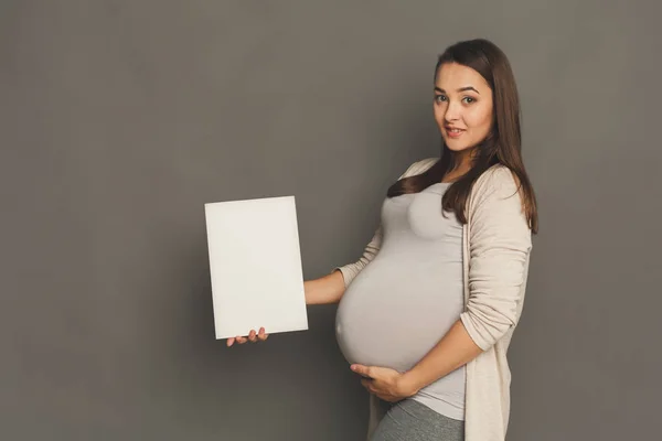 Giovane donna incinta con carta bianca bianca — Foto Stock