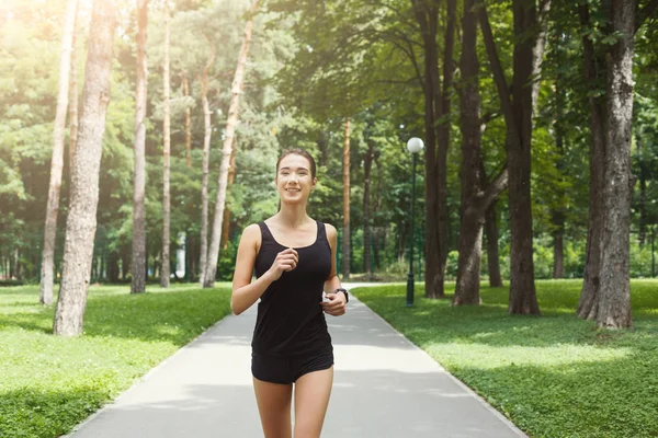 Giovane donna che fa jogging nel parco verde, copiare spazio — Foto Stock
