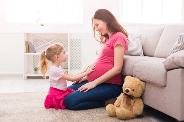 Malá dívka se dotýká její břicho těhotné matky — Stock fotografie