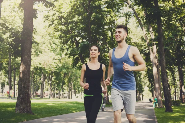 Young woman and man jogging in green park, copy space — Stock Photo, Image